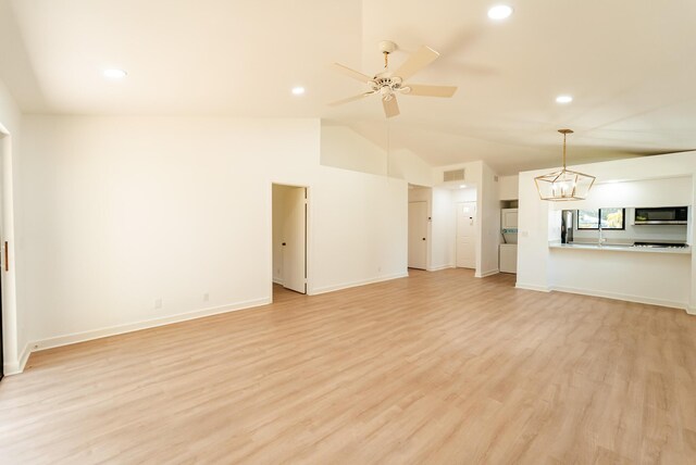 unfurnished living room featuring light hardwood / wood-style floors, ceiling fan with notable chandelier, and lofted ceiling