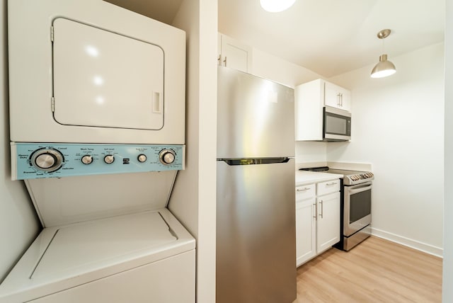 clothes washing area featuring stacked washer / dryer and light hardwood / wood-style flooring