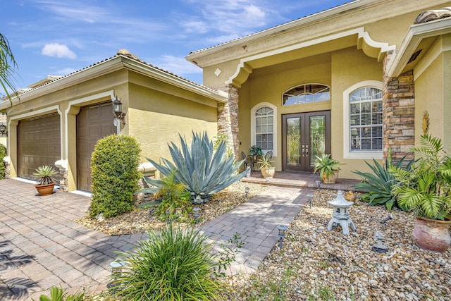 view of exterior entry with a garage and french doors