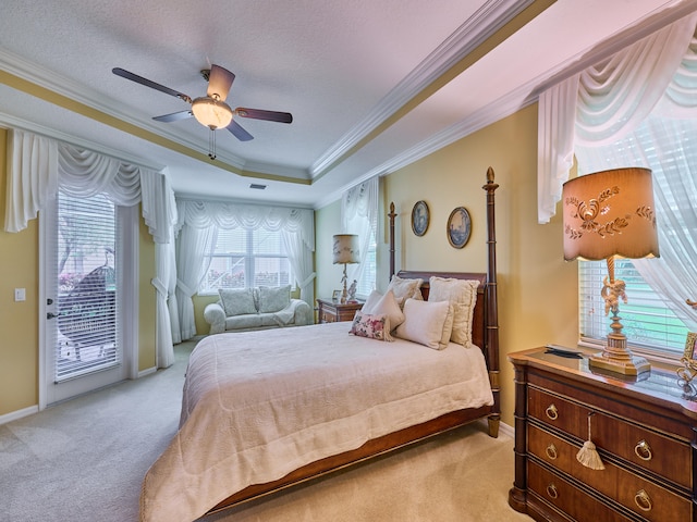 bedroom featuring light carpet, ornamental molding, access to outside, a tray ceiling, and ceiling fan