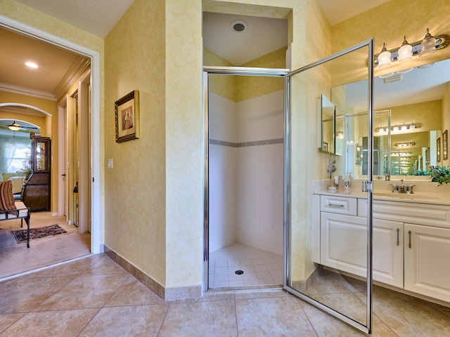 bathroom with tile patterned floors, vanity, a shower with shower door, and ornamental molding