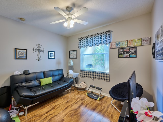 living room featuring ceiling fan, wood-type flooring, and a textured ceiling