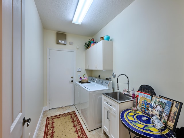 washroom with cabinets, a textured ceiling, sink, washing machine and dryer, and light tile patterned flooring