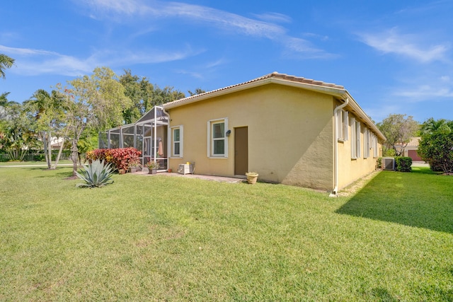 back of house with central air condition unit, a lanai, and a lawn