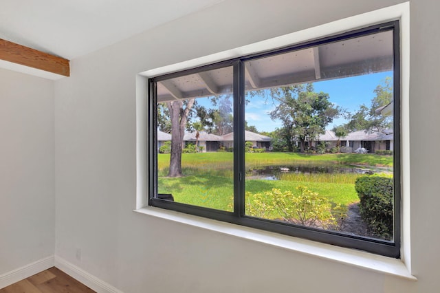 spare room with a water view, baseboards, and wood finished floors