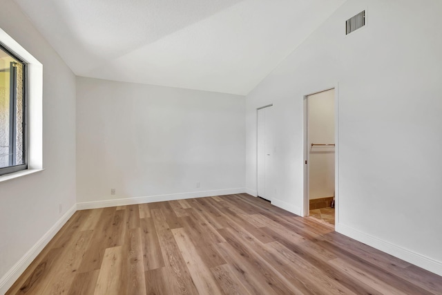 interior space featuring lofted ceiling, light wood-type flooring, visible vents, and baseboards