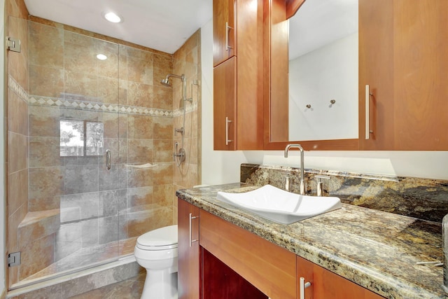 bathroom with tile patterned floors, a shower with door, vanity, and toilet