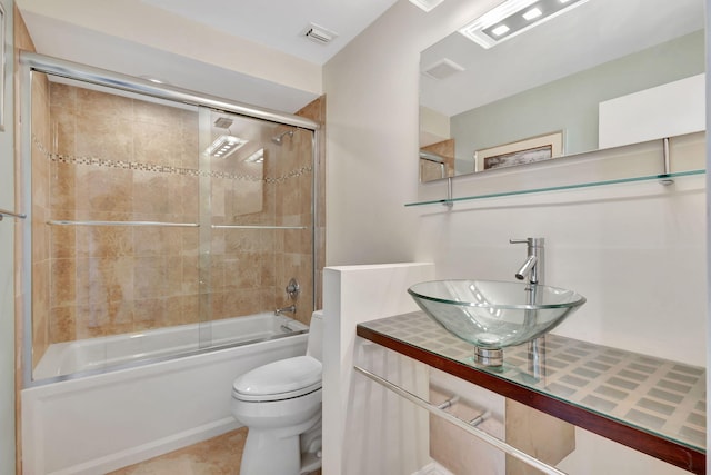 full bathroom featuring tile patterned floors, toilet, vanity, and bath / shower combo with glass door