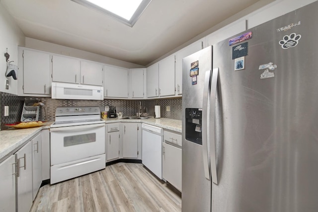 kitchen with sink, light wood-type flooring, backsplash, and white appliances