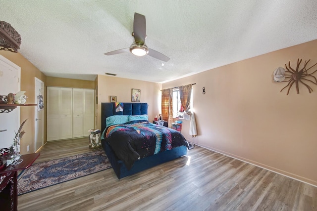 bedroom with a textured ceiling, a closet, ceiling fan, and light wood-type flooring