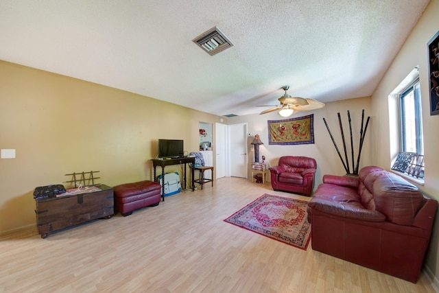 living room featuring ceiling fan, a textured ceiling, and light hardwood / wood-style flooring