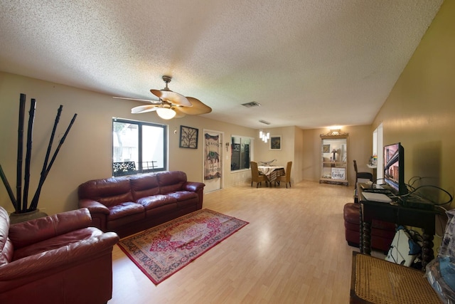 living room featuring a textured ceiling, ceiling fan, and light wood-type flooring