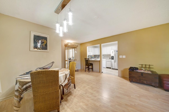 dining room with light wood-type flooring and a chandelier