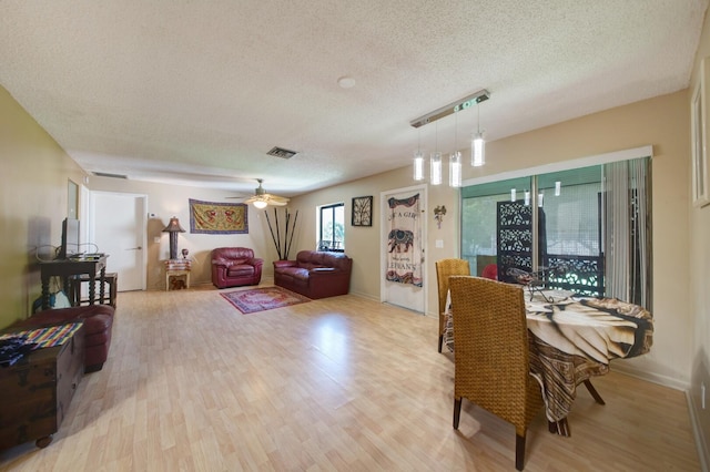 dining room featuring light wood-type flooring, a textured ceiling, and ceiling fan