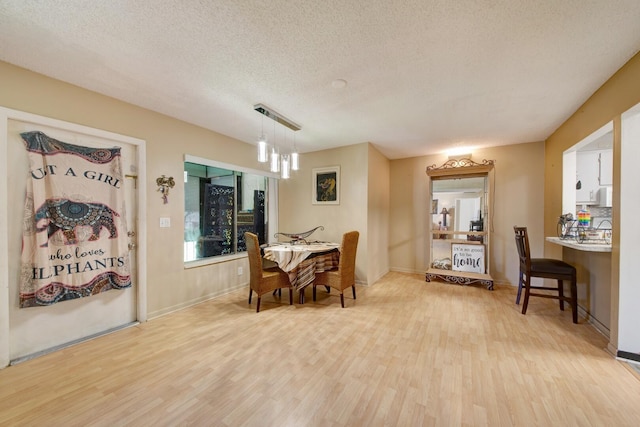 dining room featuring light wood-type flooring and a textured ceiling