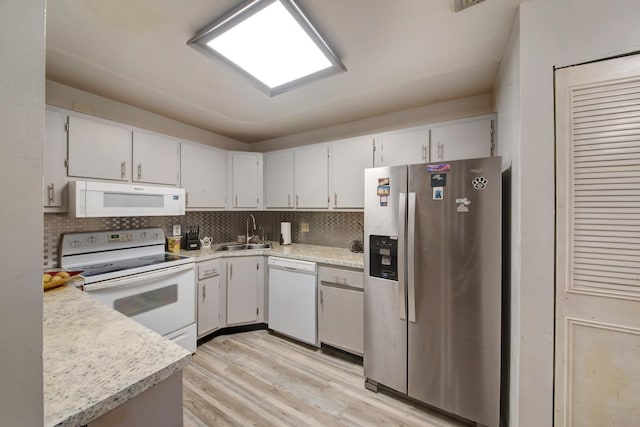 kitchen with sink, white appliances, decorative backsplash, and light hardwood / wood-style flooring