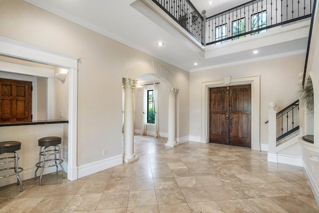 entryway with arched walkways, ornamental molding, decorative columns, and baseboards