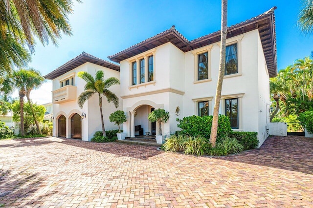 mediterranean / spanish-style house featuring a tile roof, decorative driveway, and stucco siding