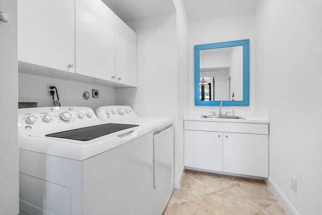 washroom featuring separate washer and dryer, a sink, cabinet space, and baseboards