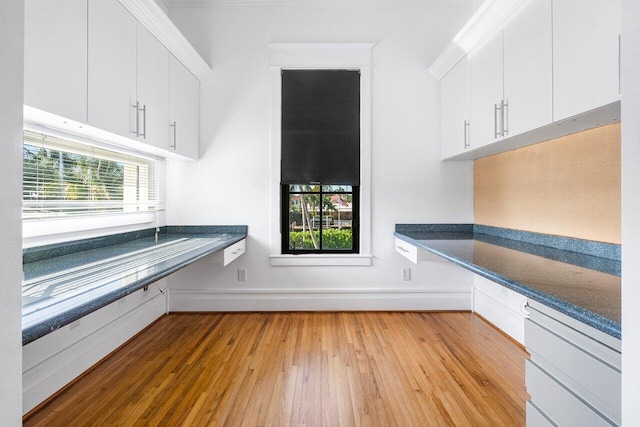 interior space featuring baseboards, light wood-style floors, and white cabinets