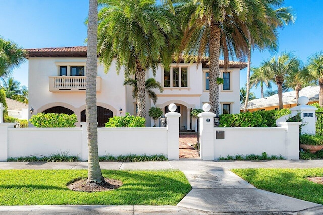 mediterranean / spanish-style home featuring a fenced front yard, a tile roof, and stucco siding