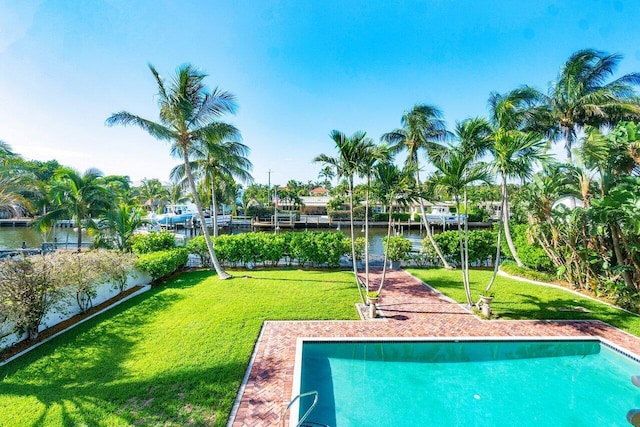 outdoor pool with a water view, a lawn, and a boat dock