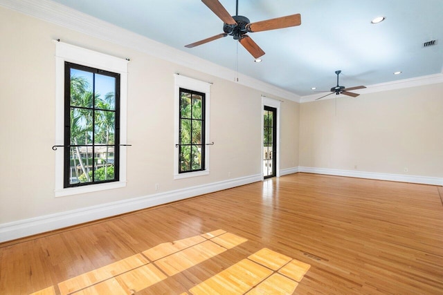 spare room with ornamental molding, light wood-style floors, visible vents, and baseboards