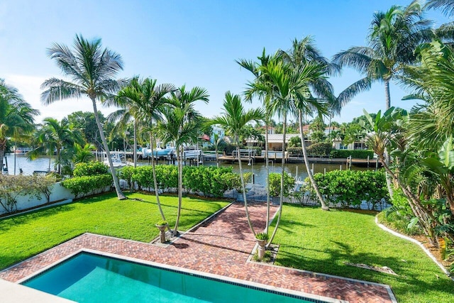 outdoor pool with a lawn, a water view, and fence