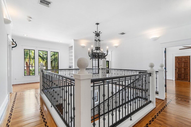 hall with visible vents, an inviting chandelier, an upstairs landing, wood finished floors, and baseboards