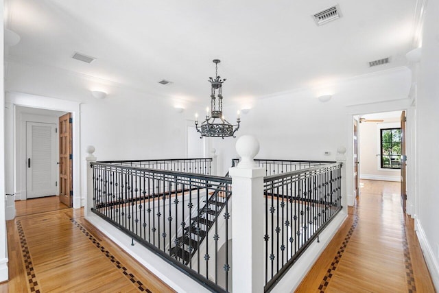 hall with visible vents, an upstairs landing, and wood finished floors