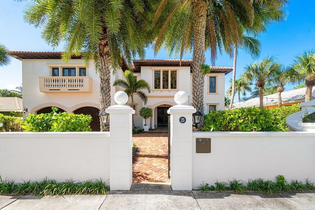 mediterranean / spanish house featuring a fenced front yard, a tiled roof, and stucco siding