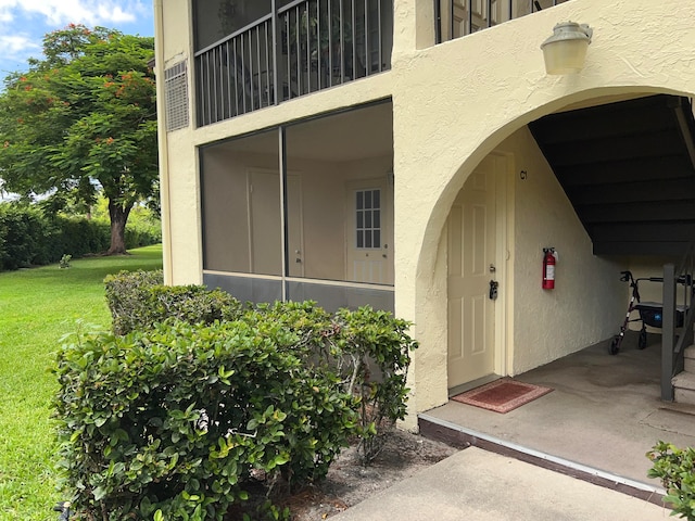 entrance to property featuring a balcony and a lawn