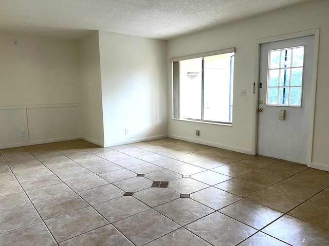 empty room featuring a textured ceiling and light tile patterned floors