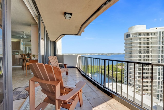 balcony with ceiling fan and a water view