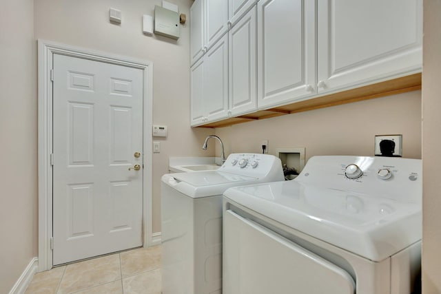 laundry area with sink, washing machine and clothes dryer, cabinets, and light tile patterned floors