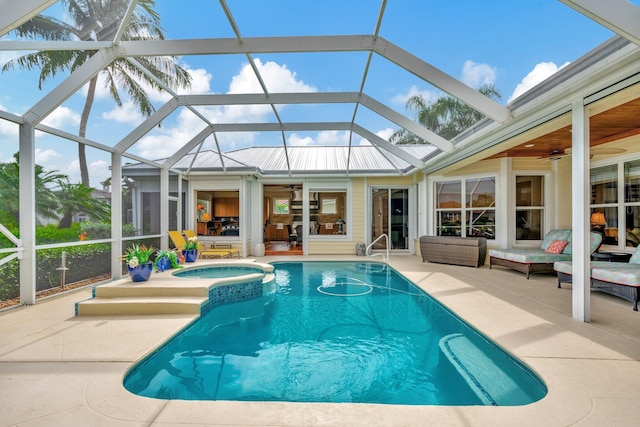 view of swimming pool with glass enclosure, ceiling fan, an in ground hot tub, and a patio area