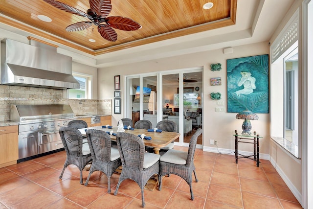 dining space with a tray ceiling, ceiling fan, and light tile patterned floors