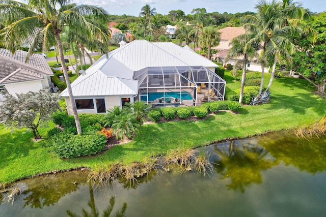 back of property featuring glass enclosure, a lawn, and a water view