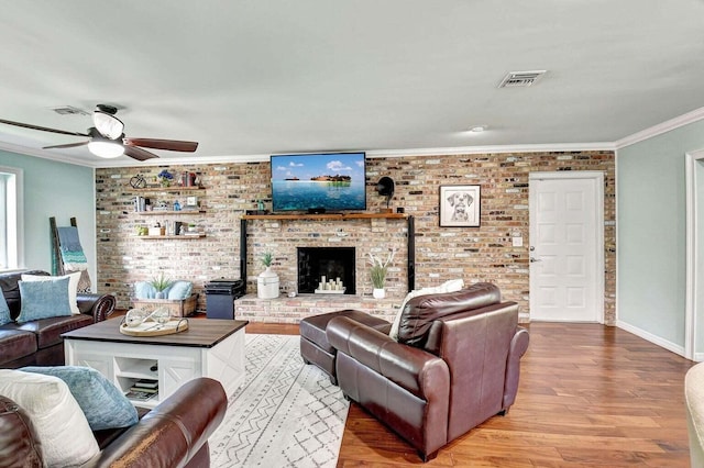 living room with visible vents, crown molding, brick wall, and wood finished floors