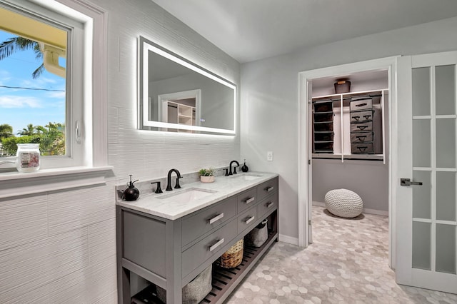 full bathroom featuring double vanity, a sink, and baseboards