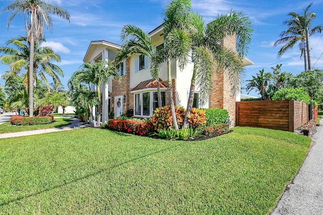 view of front of house featuring a front yard, fence, and stucco siding