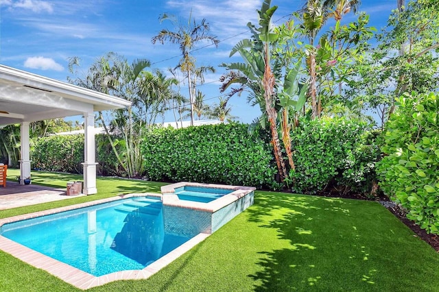 view of pool featuring a pool with connected hot tub, a yard, fence, and a patio