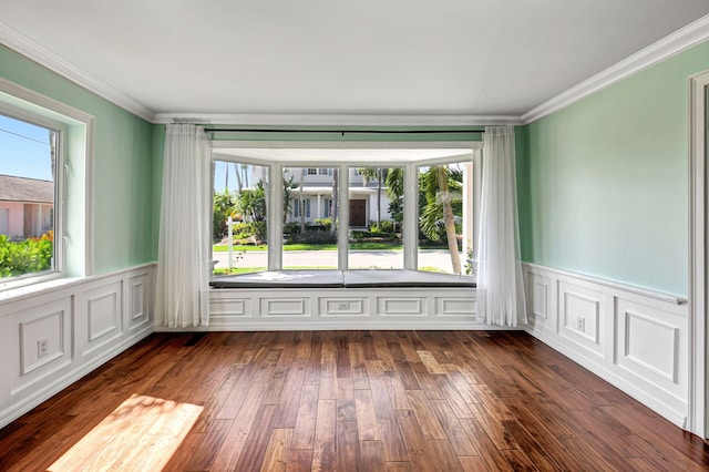 spare room featuring dark wood-style floors, crown molding, and a wainscoted wall