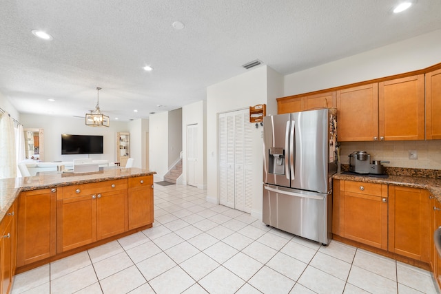 kitchen with stainless steel fridge with ice dispenser, backsplash, a textured ceiling, and light stone countertops