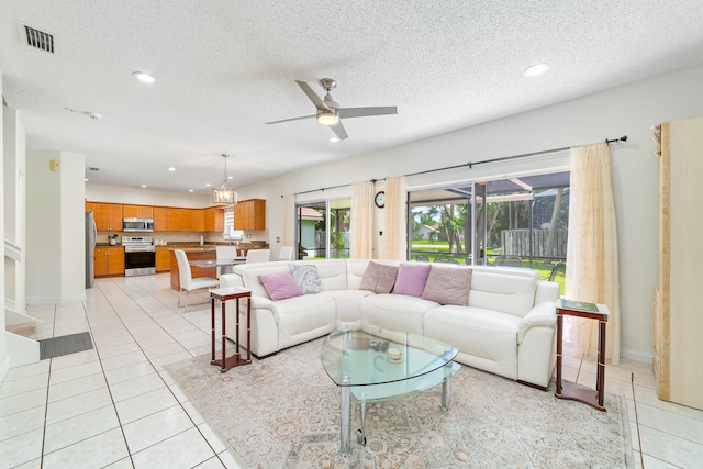 living room with a textured ceiling, ceiling fan, and light tile patterned floors