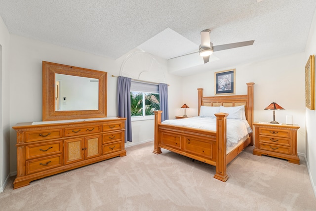 bedroom with ceiling fan, light carpet, and a textured ceiling