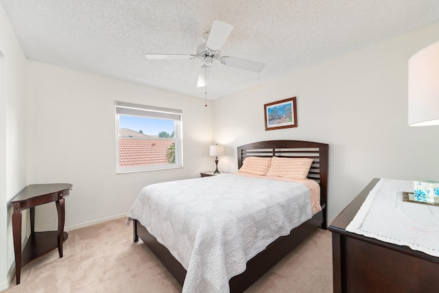 bedroom with a textured ceiling, ceiling fan, and light colored carpet