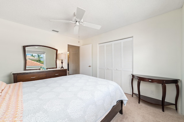 carpeted bedroom with a textured ceiling, a closet, and ceiling fan