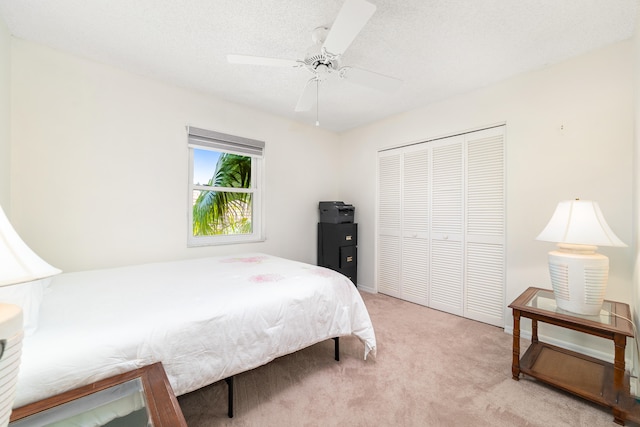 bedroom with a textured ceiling, a closet, ceiling fan, and carpet