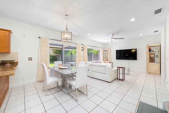 dining area with a textured ceiling, ceiling fan with notable chandelier, and light tile patterned floors